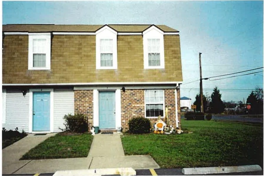 A Kent Island Village townhome end unit with brick and shingle siding and light-blue doors, seen from the street