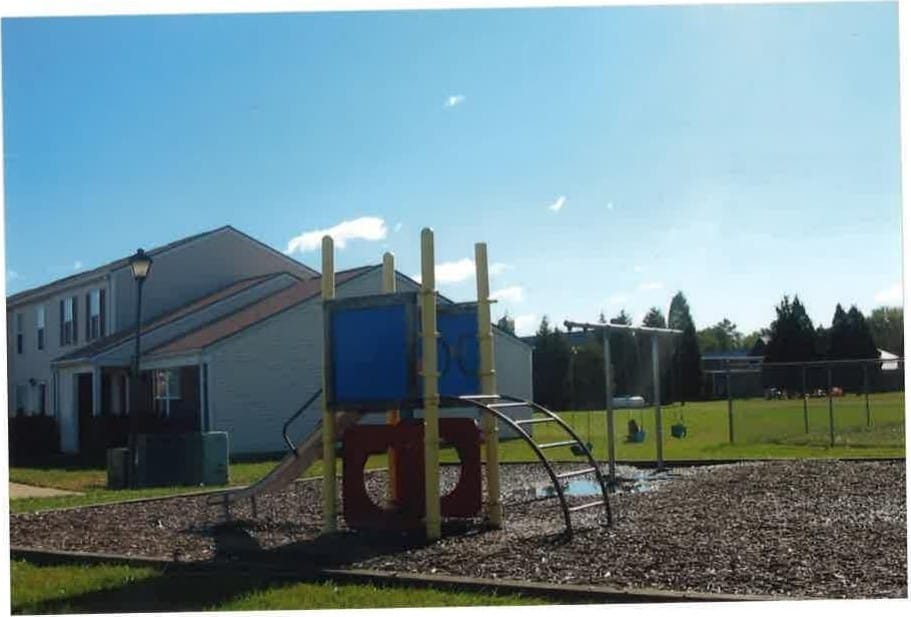 The community playground at Kent Island Village, with a slide and climbing frame beside the townhomes and an open field